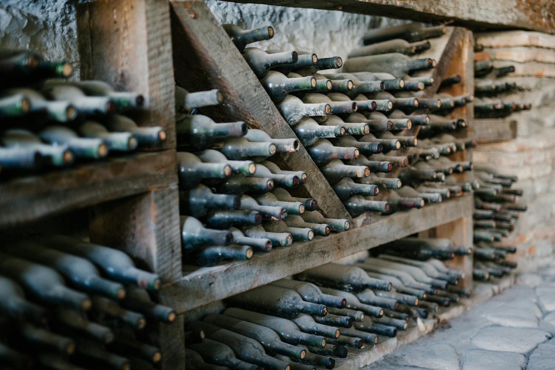 Étagères de bouteilles dans la voûte de la cave, éclairées à la lueur des bougies
